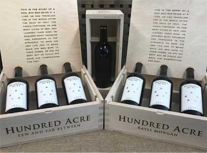 seven bottles of wine in open crates with Hundred Acre logo