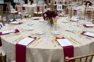 table setting with tan tablecloth and maroon napkins