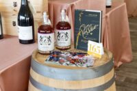 lot 165 displayed on wooden barrel with two bottles of whiskey and a signed book