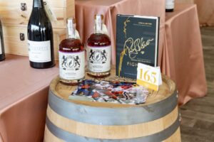 lot 165 displayed on wooden barrel with two bottles of whiskey and a signed book