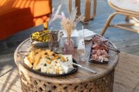 cheese, meat, and olive trays on a wicker table