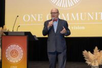 auctioneer speaks on stage with microphone next to podium