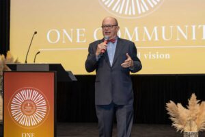 auctioneer speaks on stage with microphone next to podium