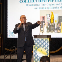 A man at a lecturn speaking into a mic for the auction