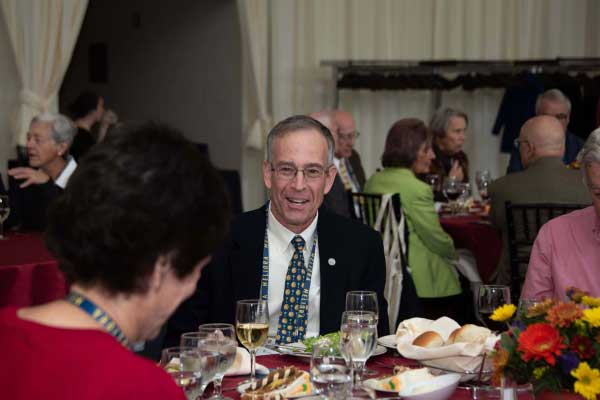 man in jacket and tie sitting at a formal dinner table