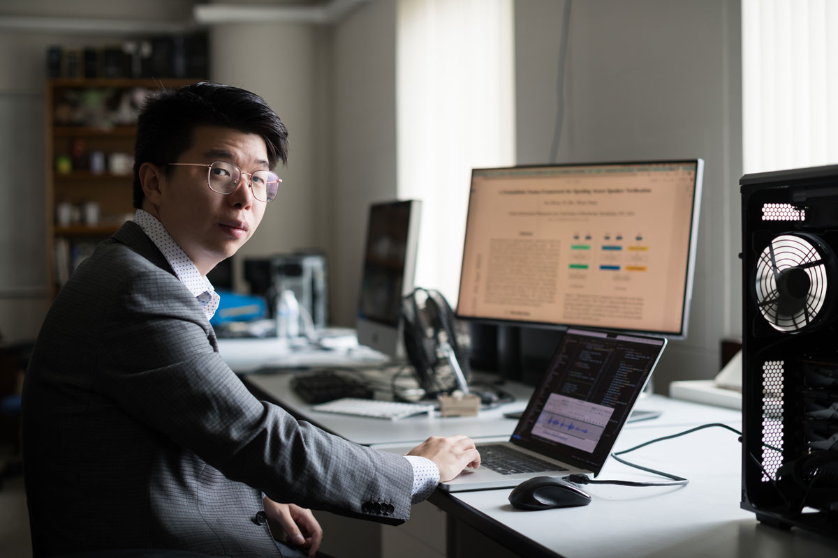 A man in a suit sits at a desk with a computer, representing University of Rochester students in a professional setting.