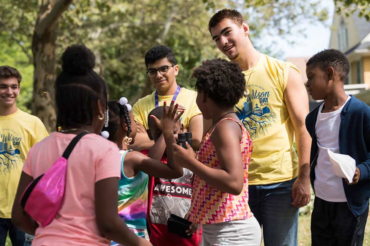A group of University of Rochester students gathers around a man during the annual volunteer service event.
