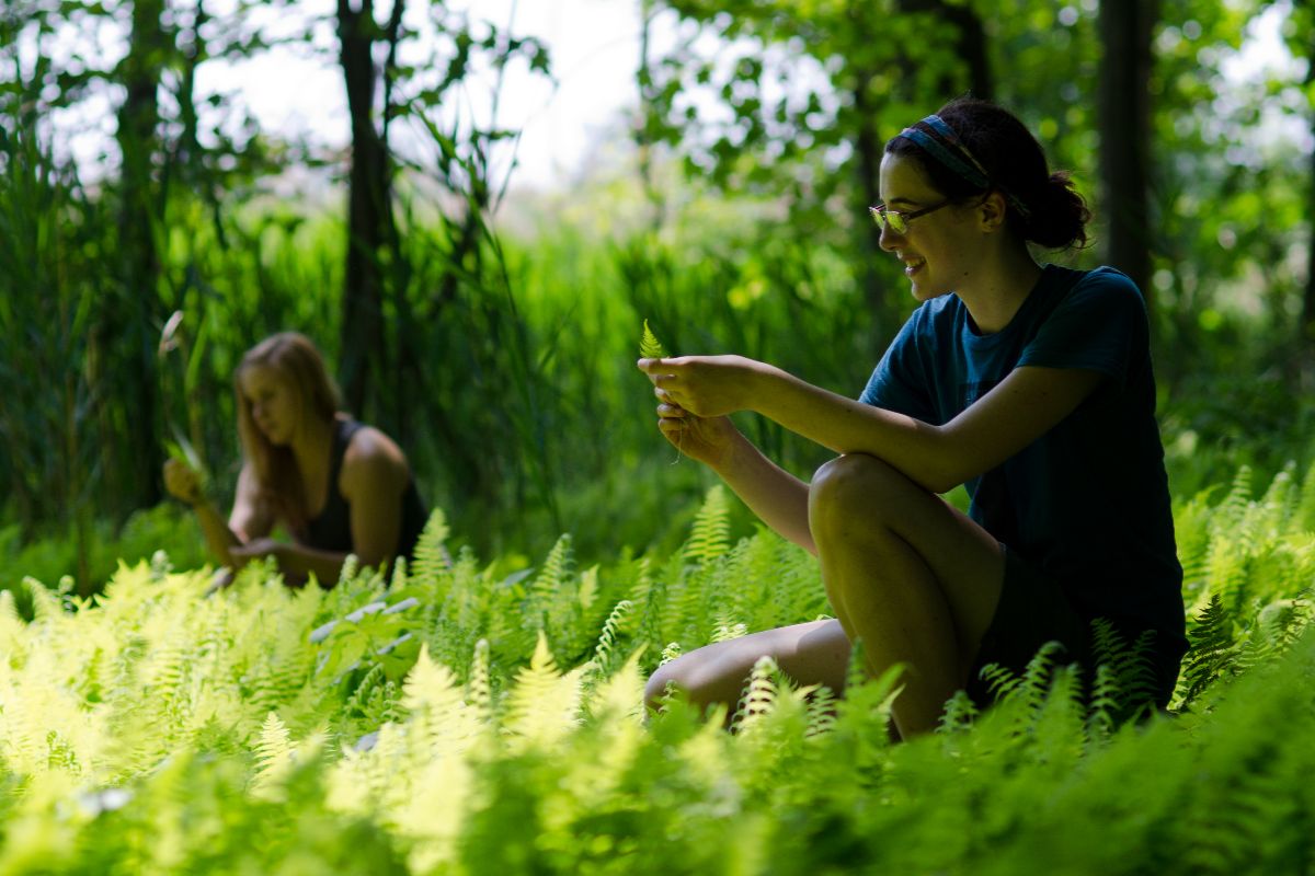 A woman sitting cross-legged on green grass, enjoying a sunny day outdoors.