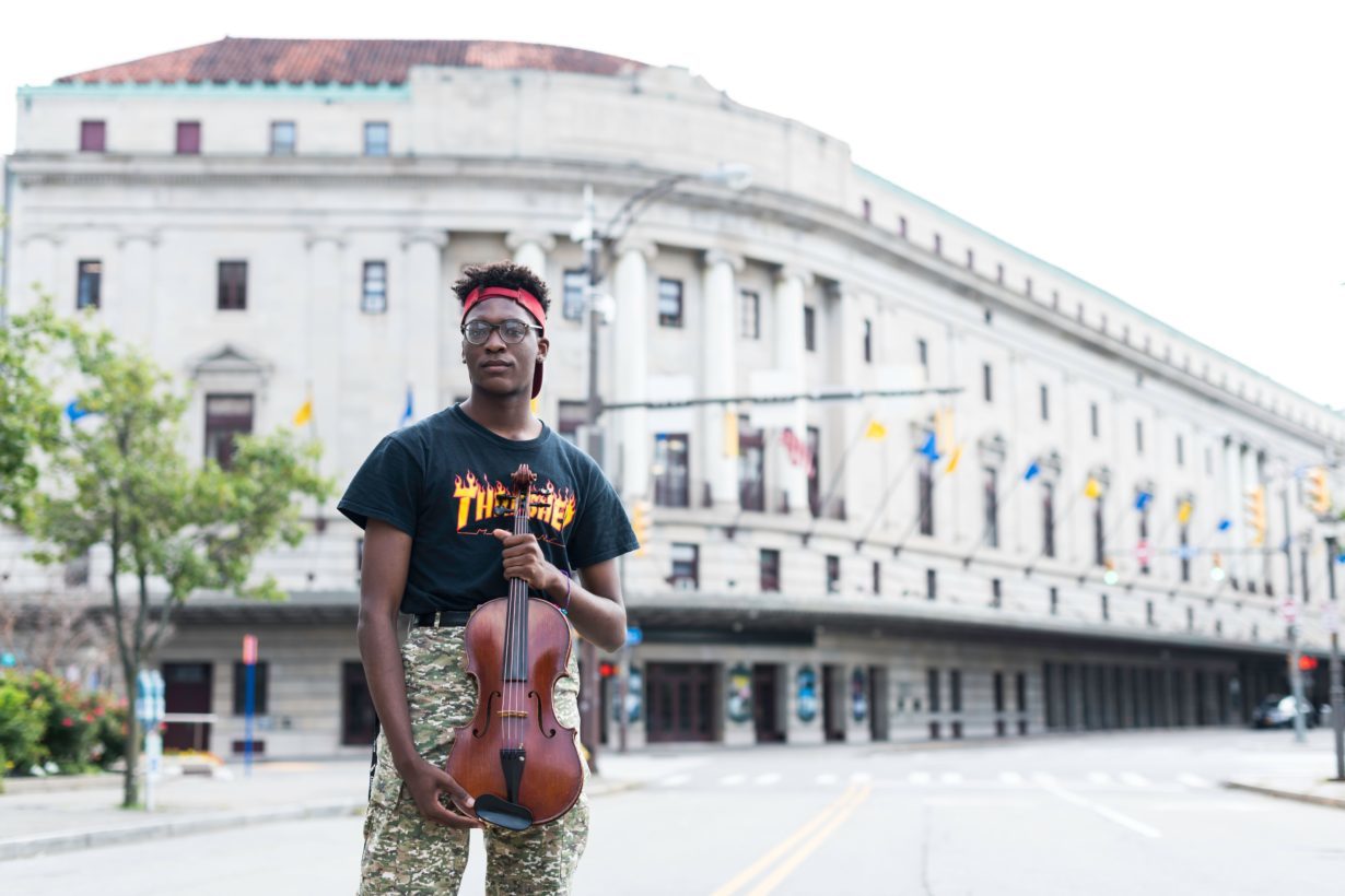 University of Rochester Eastman School of Music student holding a viola outside of Kodak Hall in Rochester