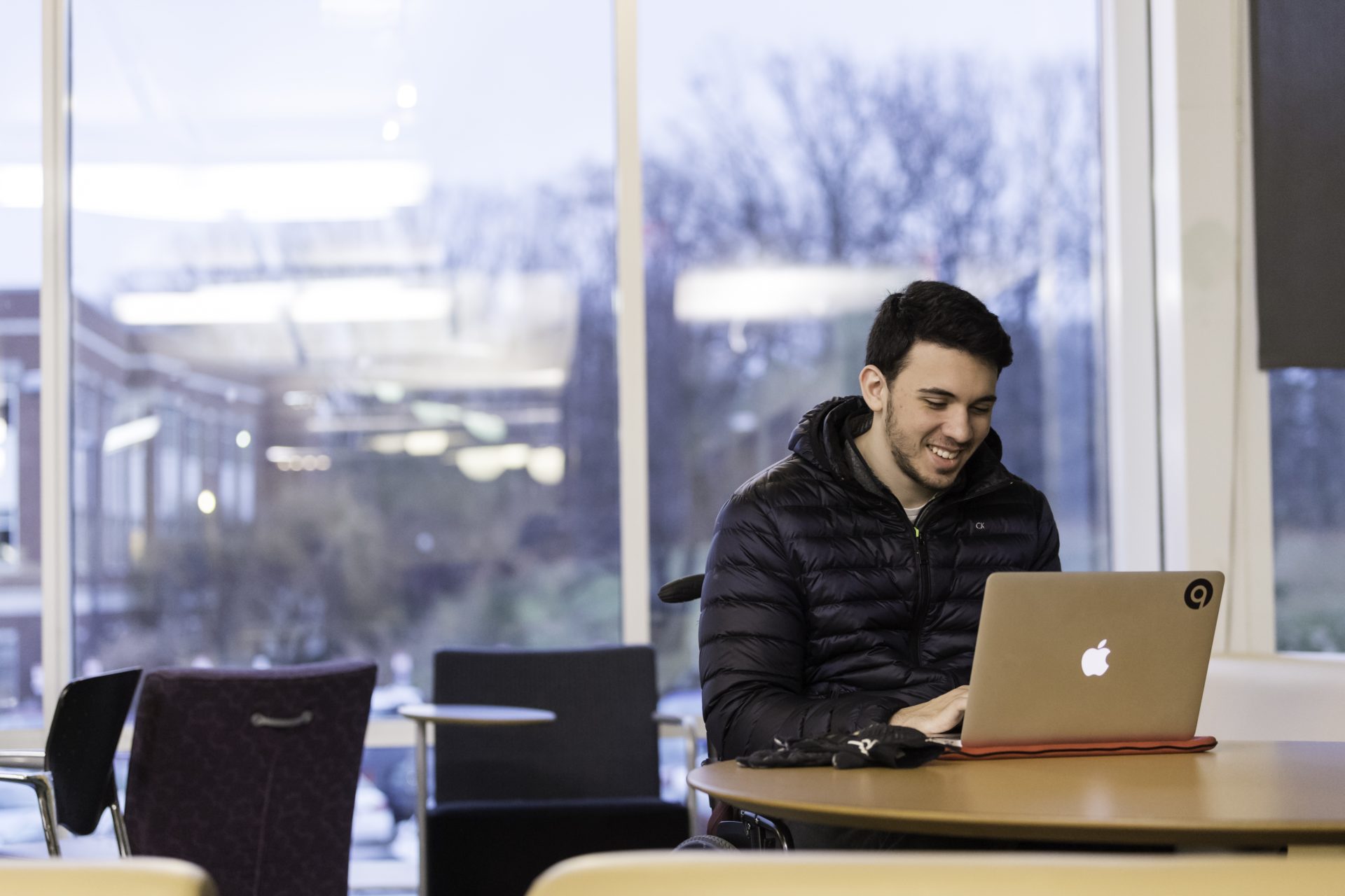 University of Rochester graduate student working on his laptop out of the Rush Rhees library