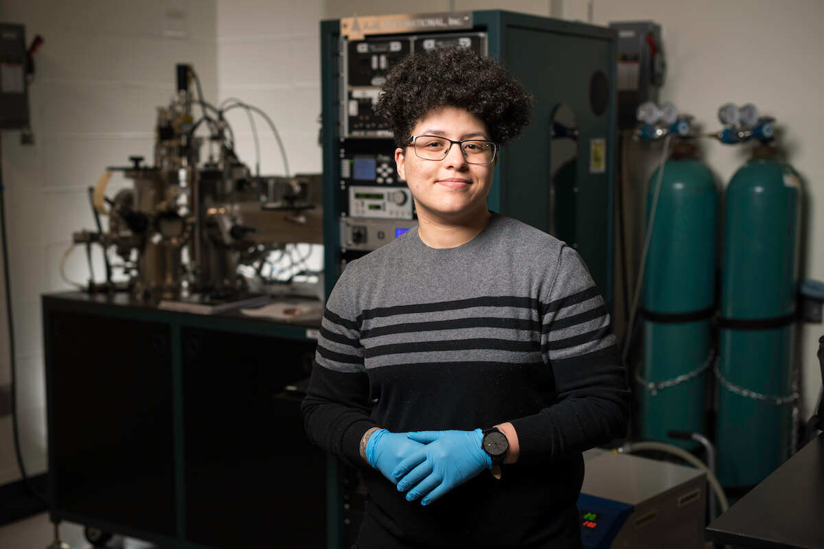 University of Rocheste student in a lab wearing gloves in front of a piece of lab equipment