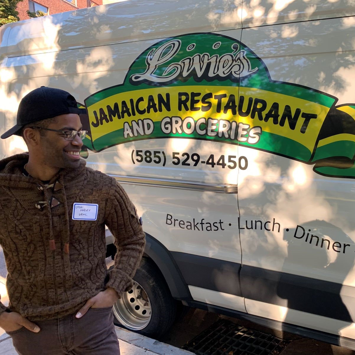 A student standing in front of a Livie's Jamaican Restaurant truck