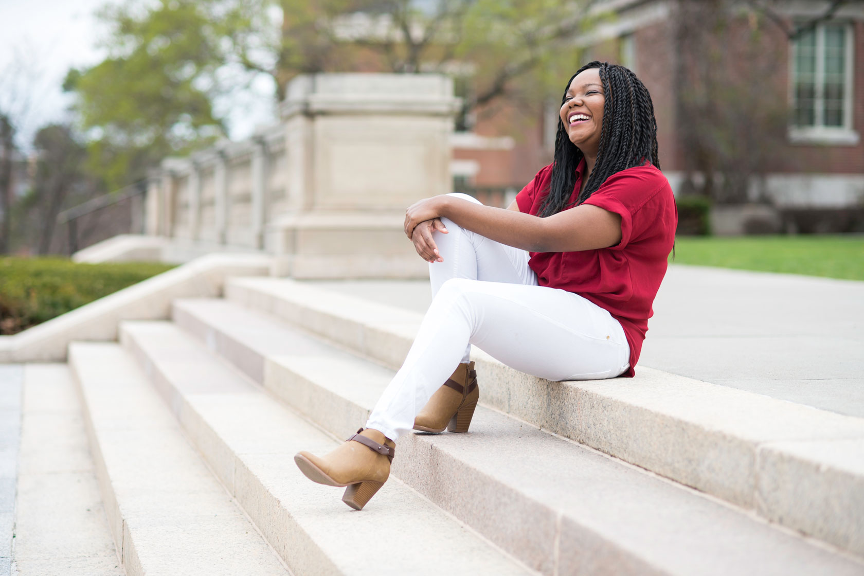 University of Rochester graduate students sitting outside on the steps to campus, laughing