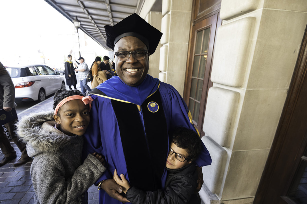 Doctoral degree graduate celebrates with his grandkids after commencement ceremony at Eastman Theatre