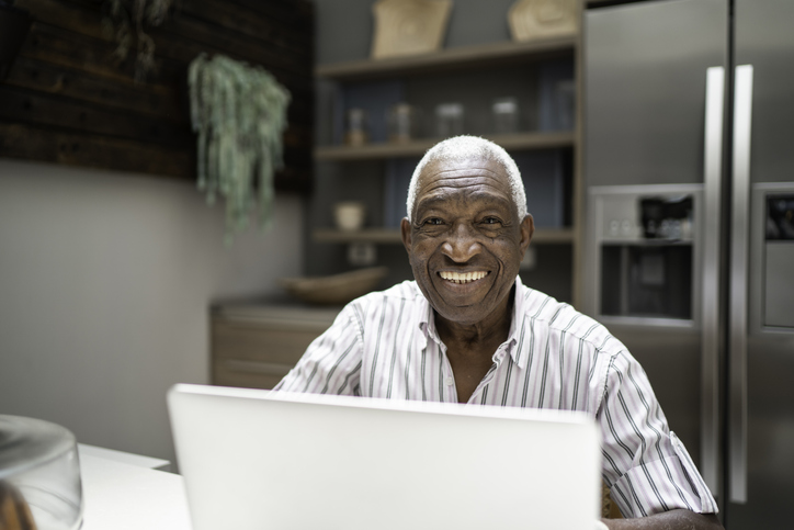 Portrait of a senior man using laptop in the kitchen table