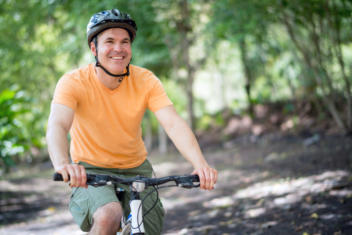 smiling man riding a mountain bike on a nature trail