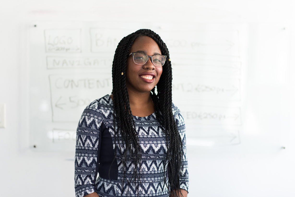 woman in an office setting smiling in front of a white board