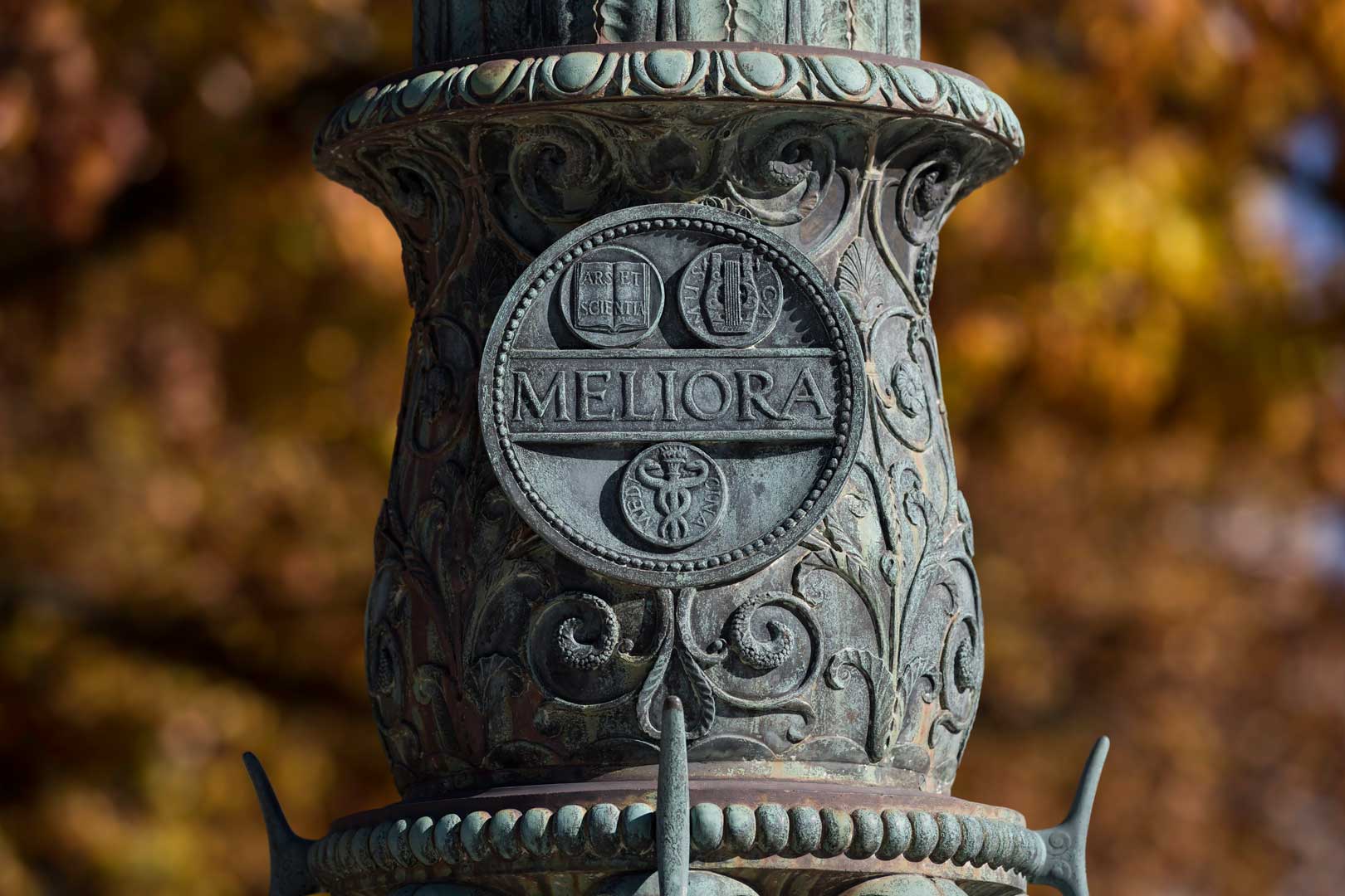 Close-up of the Meliora seal inscription on flagpole on Eastman Quad at the University of Rochester