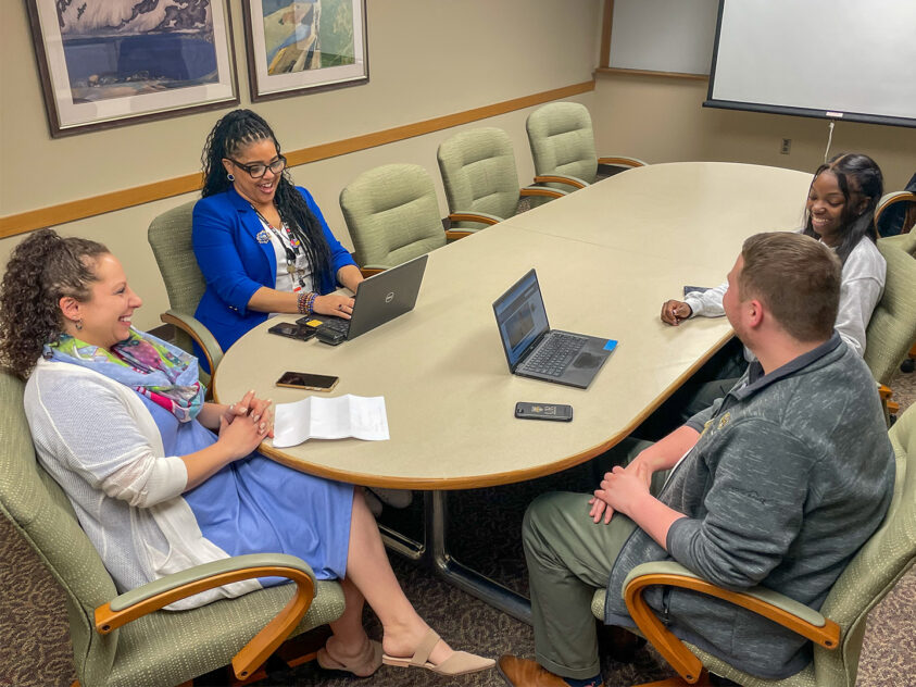 Team meeting with four people sitting in a conference room.