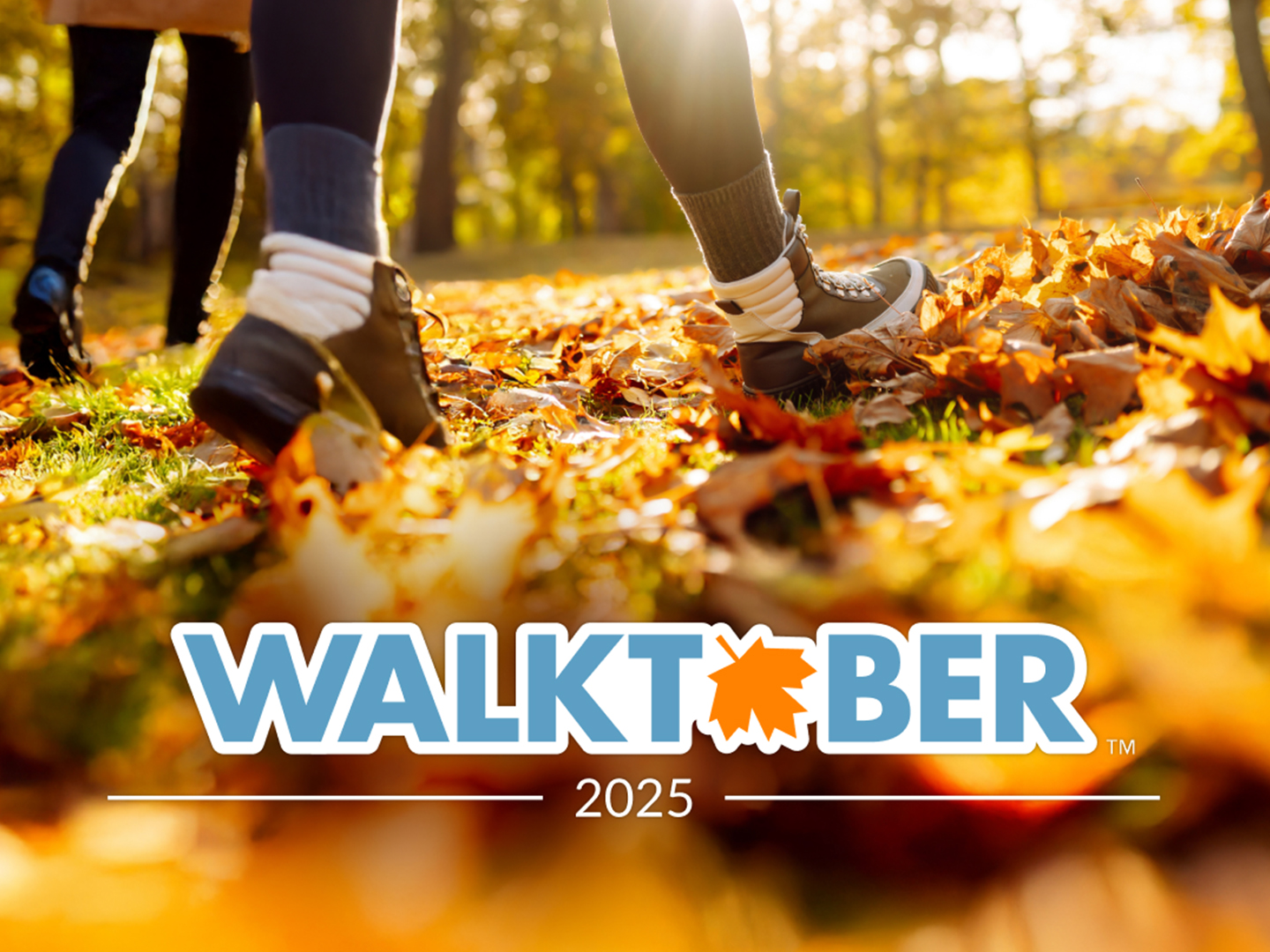 Two people walking in the woods with fall foliage with the logo 'Walktober' at the bottom center.