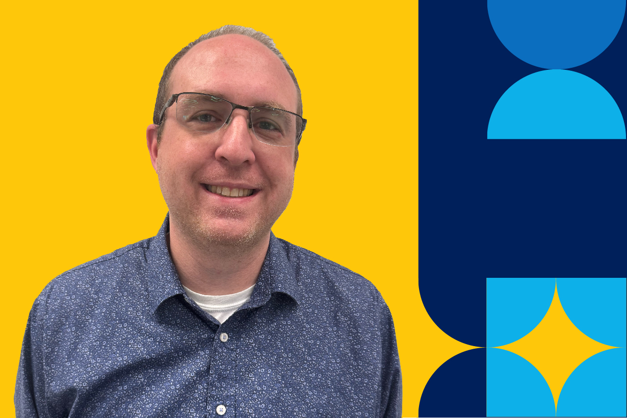 A man named, Alois Romamowski, smiling in a blue patterend button down shift bust up.