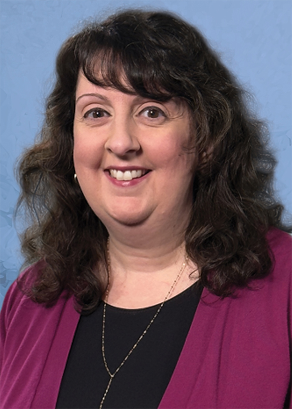 A woman named, Deborah Thompson, smiling brightly in a burgundy sweater and black shirt with wavy shoulder length hair.
