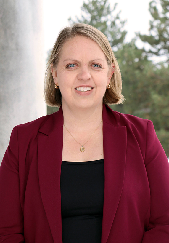 A woman named, Erica Owens in a red blazer and black shirt with neck length blonde hair.