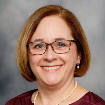 A woman named, Karen Scott, smilling brightly with her teeth showing. 