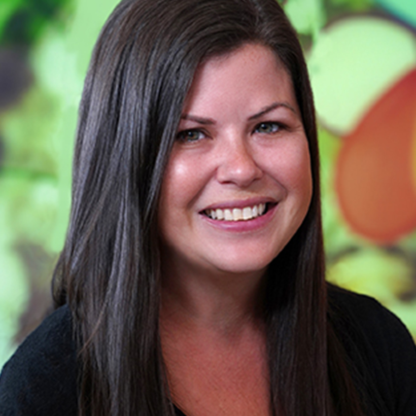 A woman named Amy Kelley is smiling brightly in front of an abstract art painting.