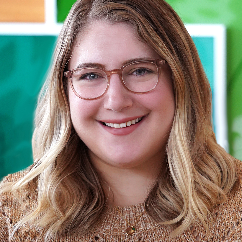 A woman named Jessica Milnikiewicz smiling brightly in front of a abstract art painting.