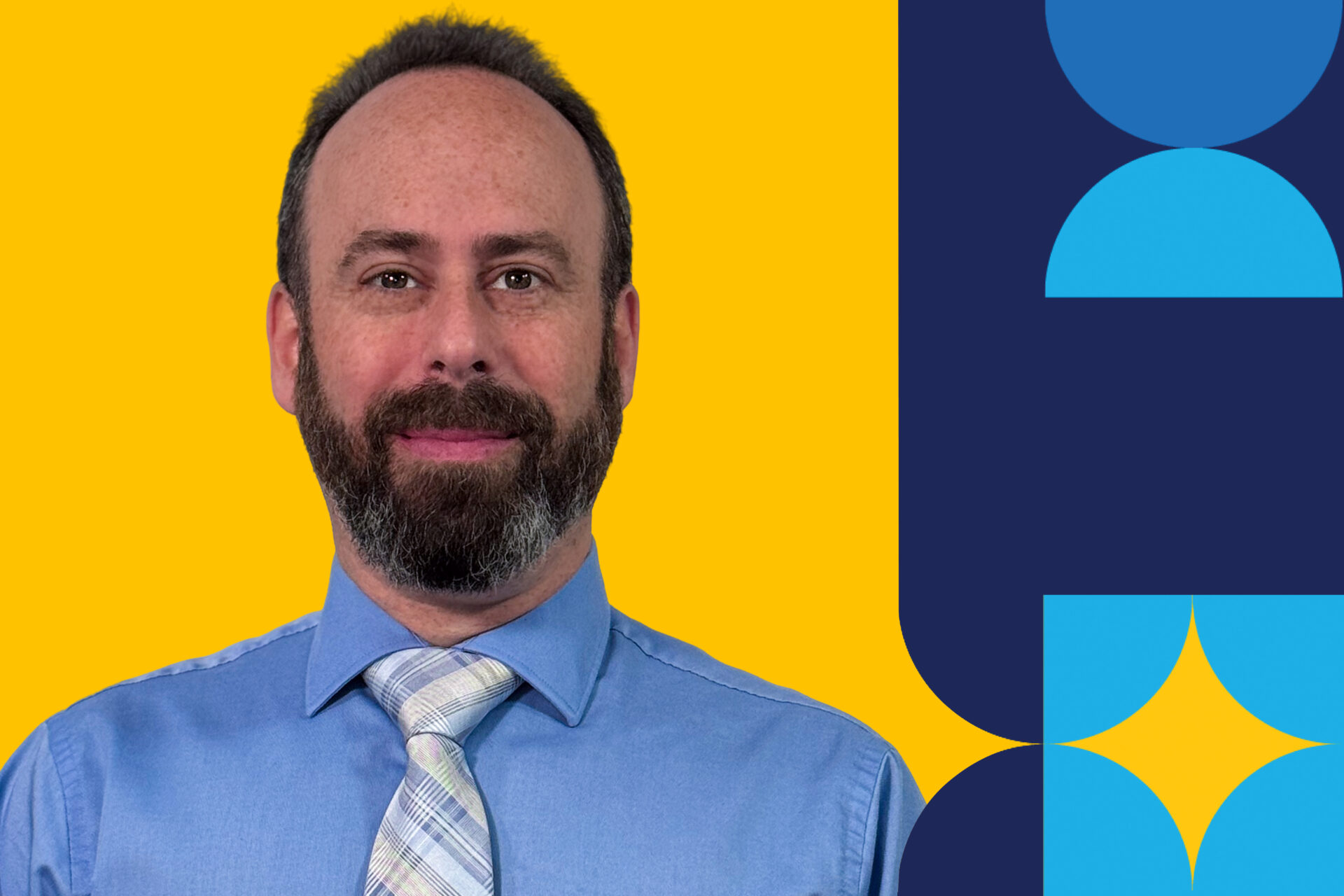 A man named Neil Seligman bust up in a light blue button down in front of a yellow background.