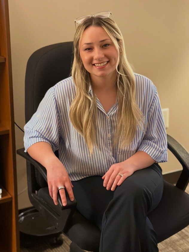 A woman named Zoe Carlson sitting on a chair.