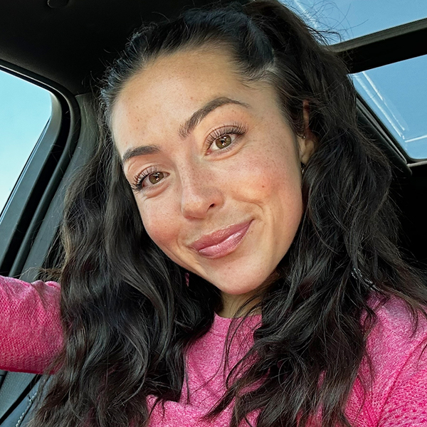 A woman named Carmella Rodger is smiling with her head slightly tilted to the left in a car.