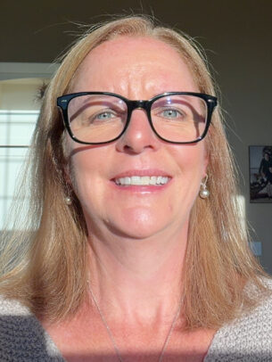 A woman named Kim Morgan is smiling brightly, wearing glasses with shoulder-length hair.