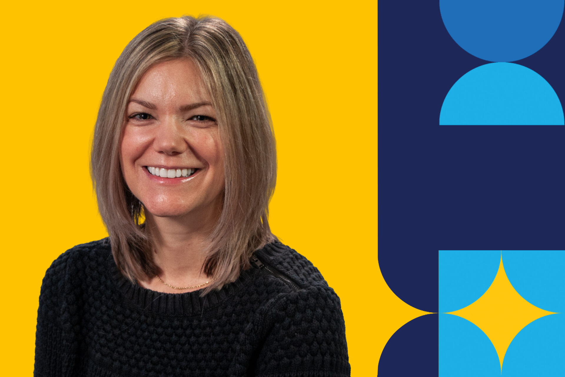 A woman named Liz Fritz smiling brightly with short hair and wearing a black shirt in front of a yellow background.