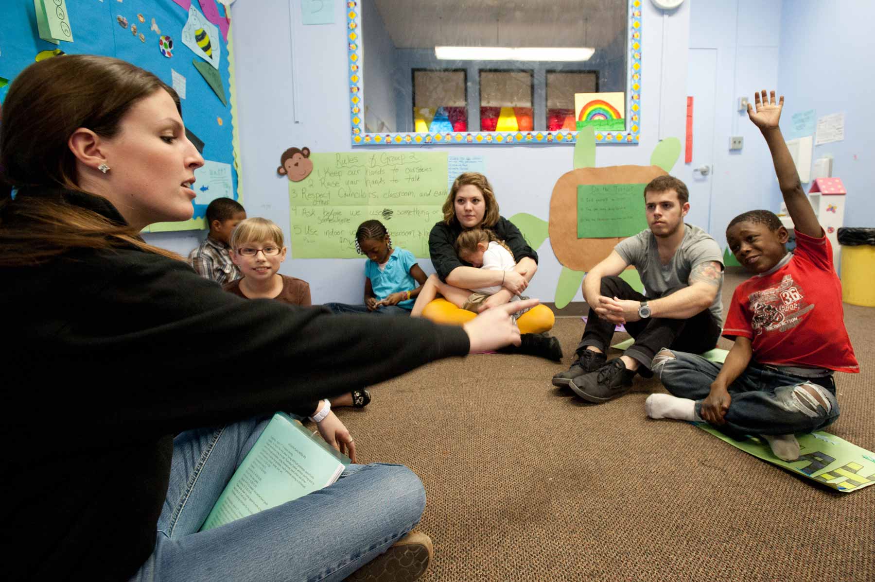 students with teacher sitting on the floor in a classroom