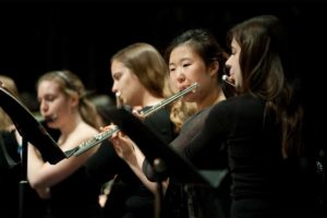 row of flute players in the middle of a performance