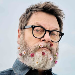 Nick Offerman headshot, with flowers in his beard