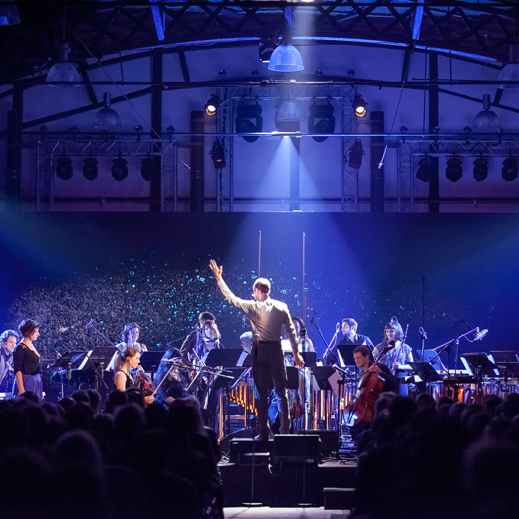 A conductor conducting an orchestra in blue light