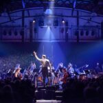 A conductor conducting an orchestra in blue light