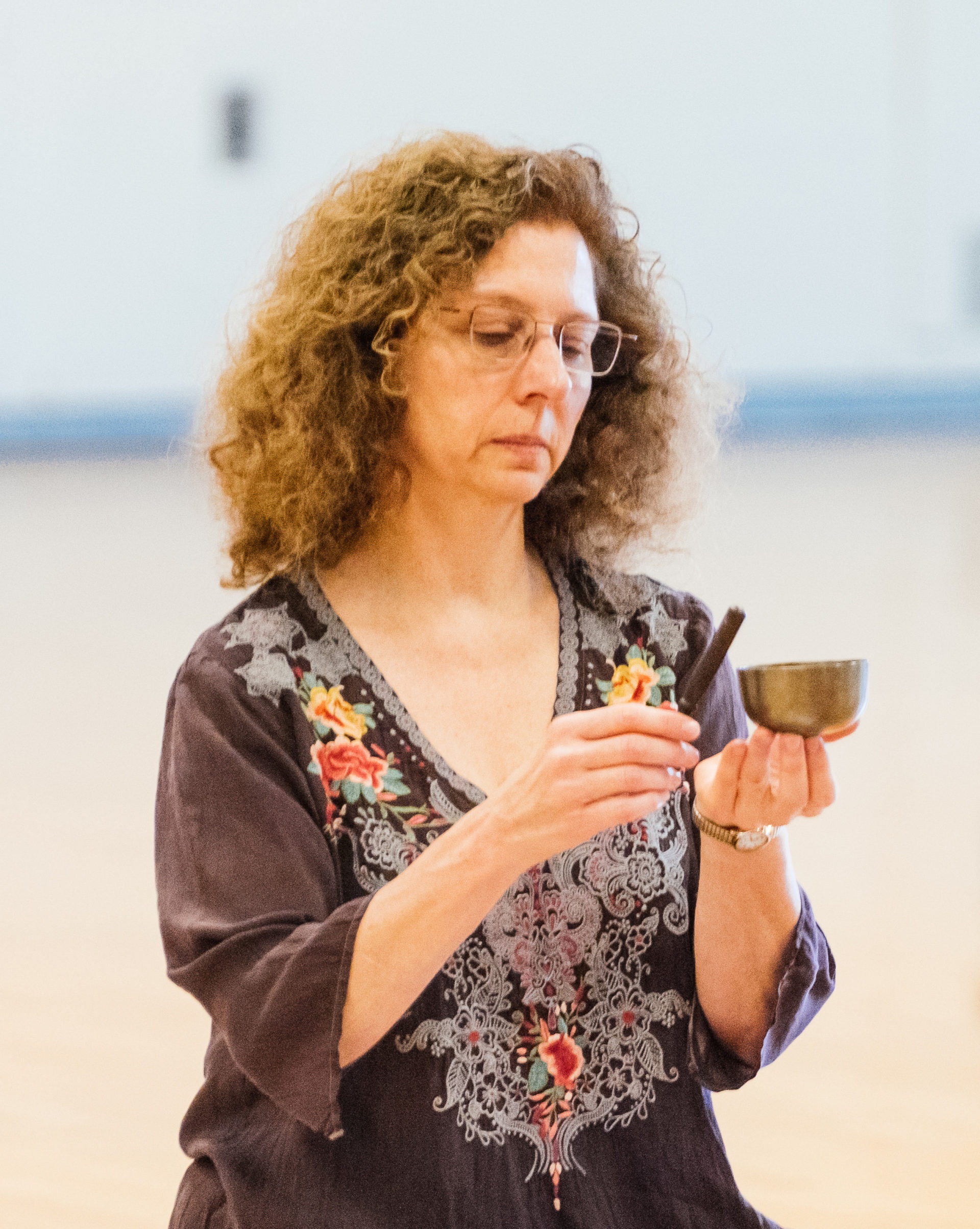 Picture of a woman ringing a singing bowl during a meditation.