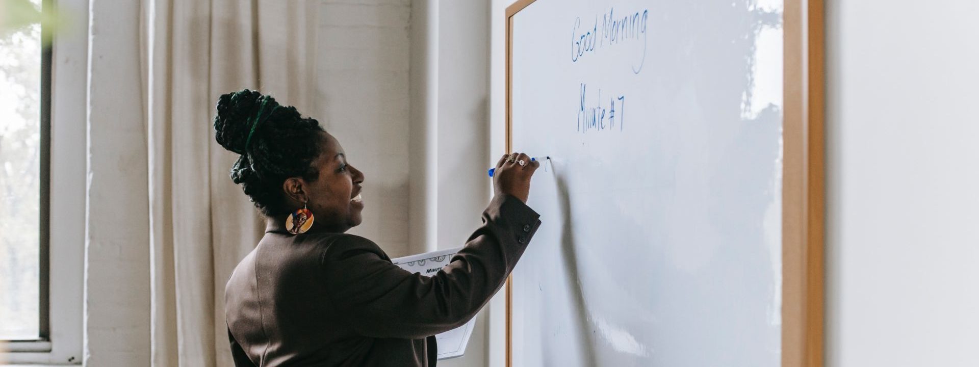 A teacher writing on a white board in class.