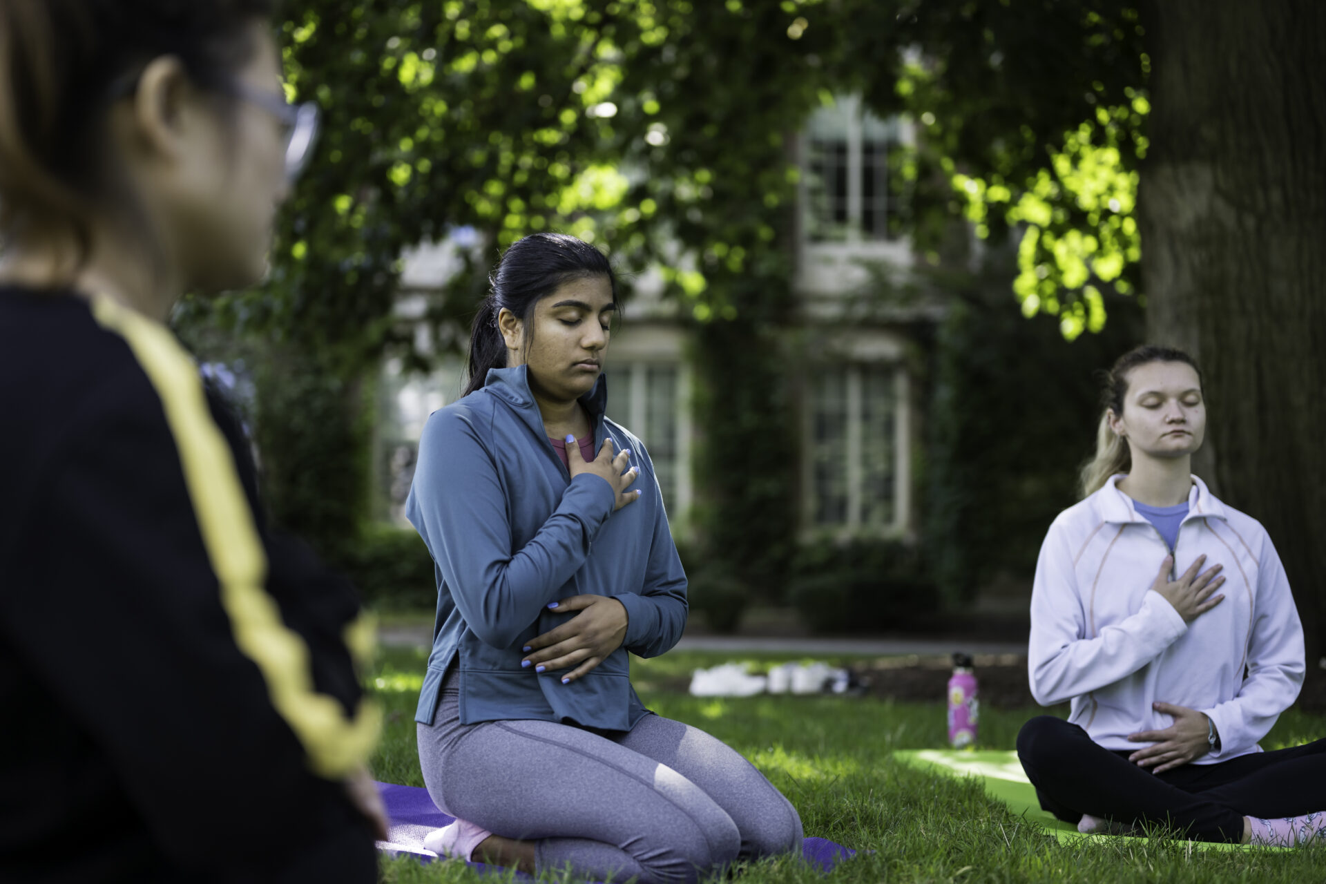 Students with one hand on heart and one on belly in meditation postures