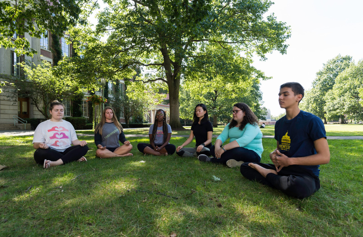 Students in meditation postures on the Eastman Quad