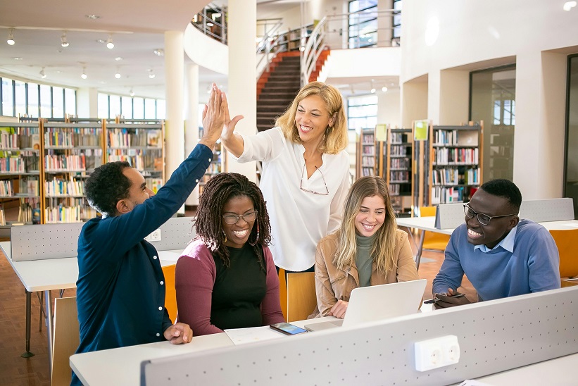 Team of people celebrating and high-fiving in an office