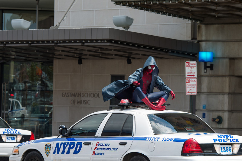 spiderman atop a polic car in front of Eastman Theatre