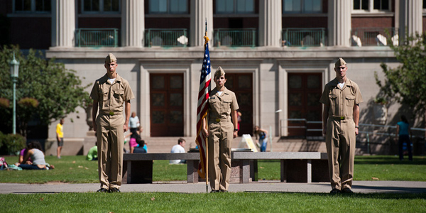 Feature image NROTC midshipmen with flag in front of Rush Rhees