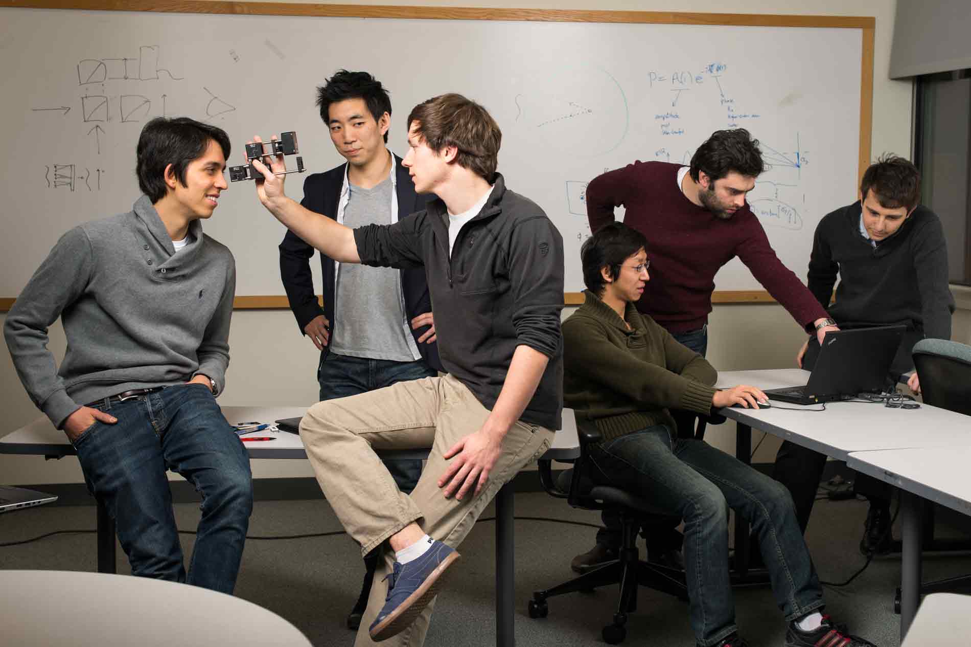 Feature image students in a lab pose with the optical device