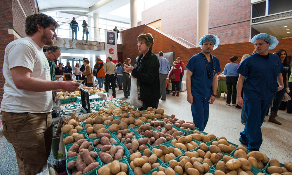 Feature image people shopping for potatoes as men in medical scrubs look on