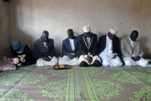 men (and one woman) kneeling in prayer